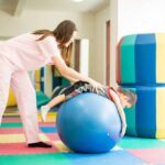 fisioterapeuta en sesión fisioterapia pediátrica con infante pelota