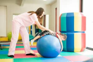 fisioterapeuta en sesión fisioterapia pediátrica con infante pelota