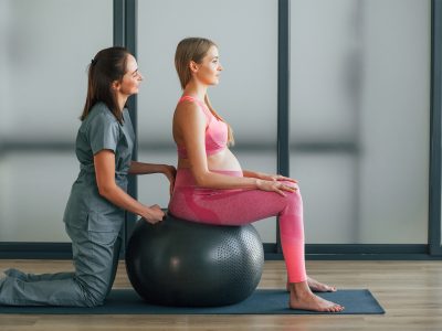 Pregnant woman in pink clothes. In health center getting help by doctor Pregnant woman in pink clothes. In health center getting help by doctor.