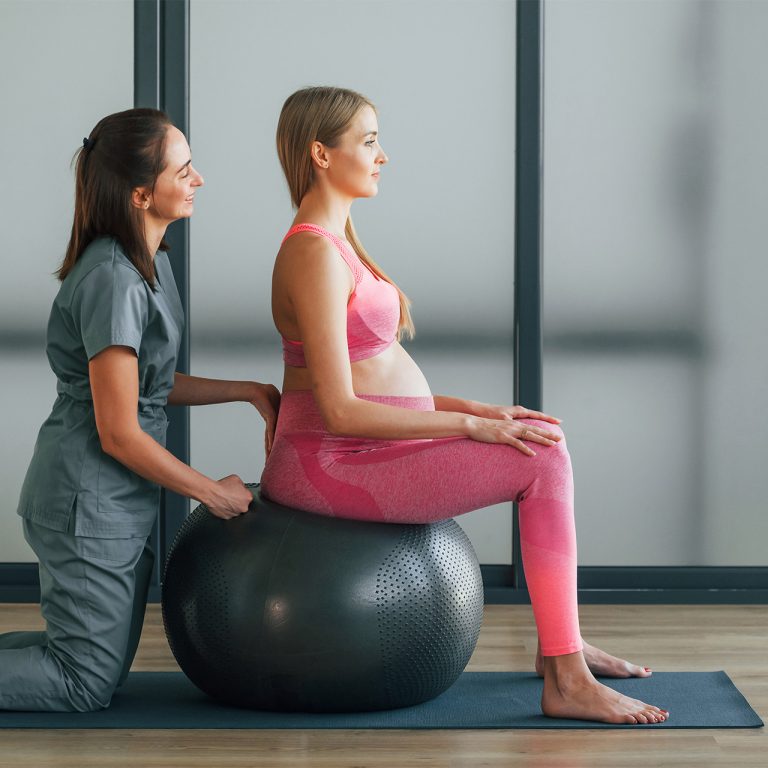 Pregnant woman in pink clothes. In health center getting help by doctor.